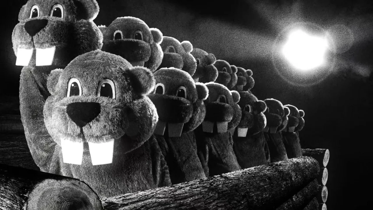 Hundreds of Beavers (2022) movie still: medium — A line of fluffy beaver mascots stands on top of a constructed wooden log barrier. A bright light…
