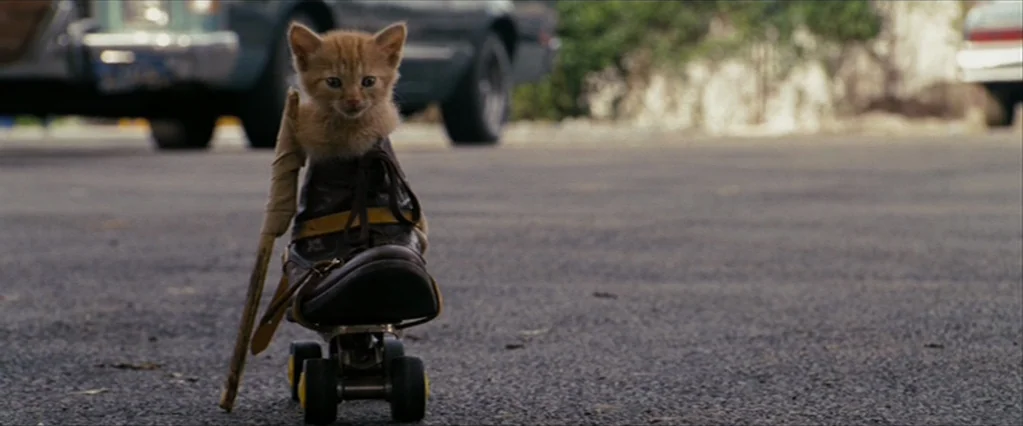 The Brothers Bloom (2008) movie still: medium — A small ginger kitten sits inside a leather boot attached to four roller skate wheels. The kitten is…
