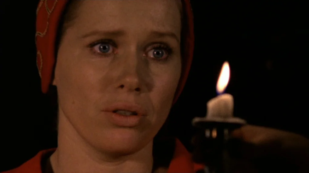 Face to Face (1976) movie still: closeup — A woman stares into the darkness while lit by the flicker of a candle. The frame is pitch black with only…