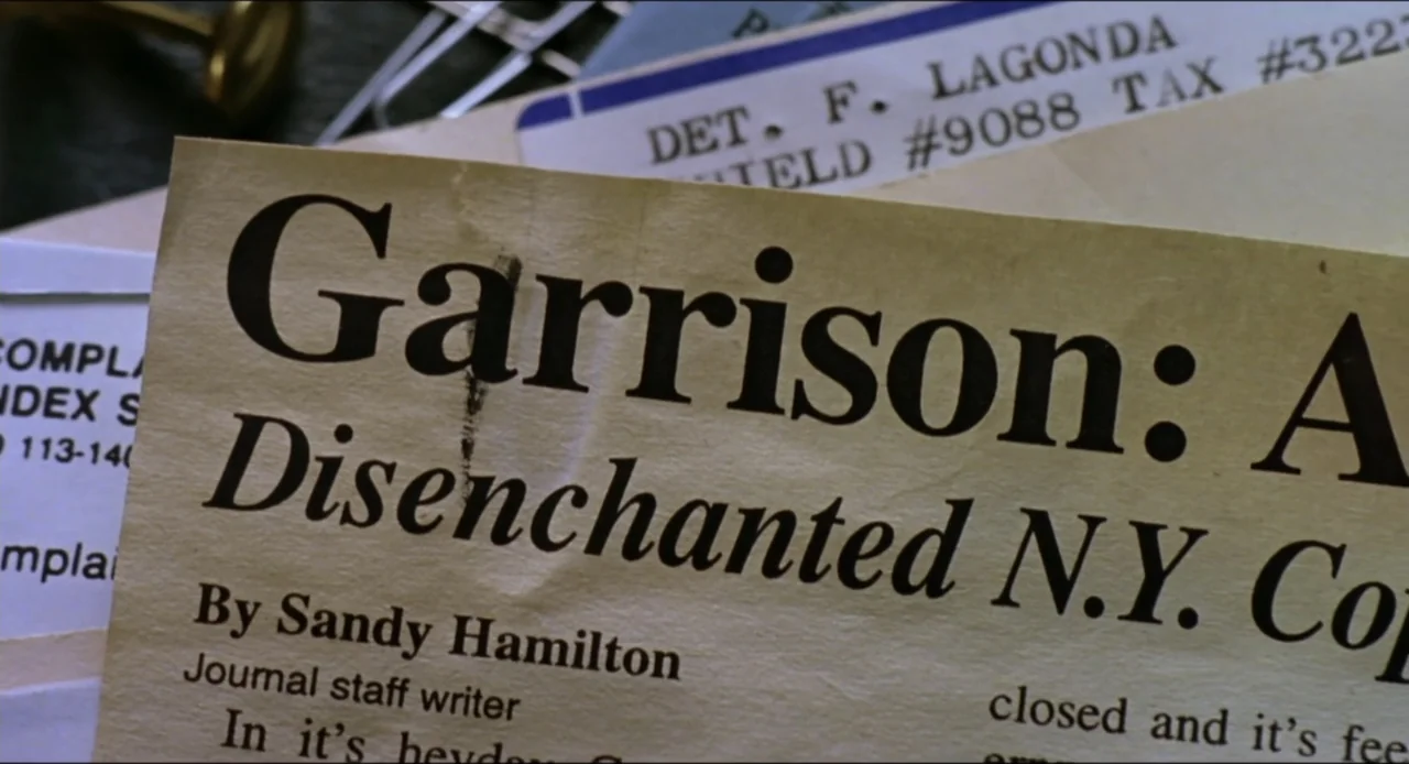 Cop Land (1997) movie still: closeup — A close-up view of several stacked printed paper documents and official forms on a surface. The top sheet is…