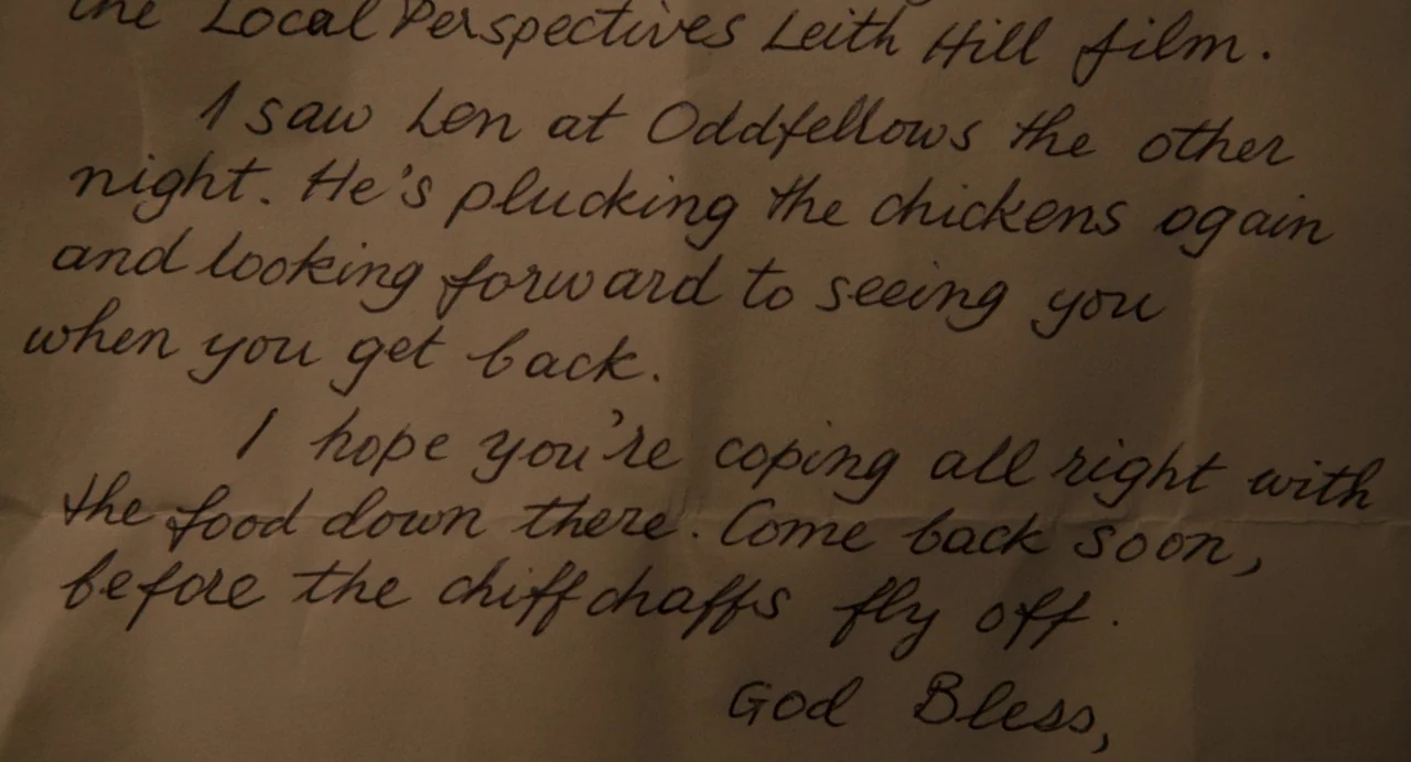 Berberian Sound Studio (2012) movie still: closeup — A cream-colored sheet of paper contains handwritten cursive text in dark ink. The paper appears…