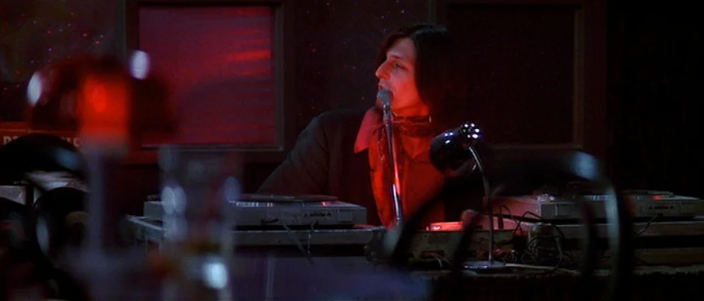 The People vs. Larry Flint (1996) movie still: medium — A dimly lit room filled with sound mixing equipment and broadcasting gear. A man with long…