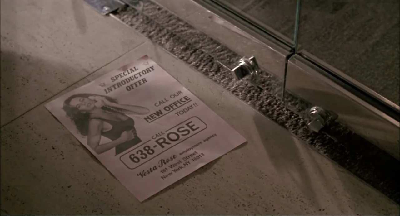 She-Devil (1989) movie still: closeup — A promotional advertisement flyer rests on a light speckled tile floor. The paper features text and an…