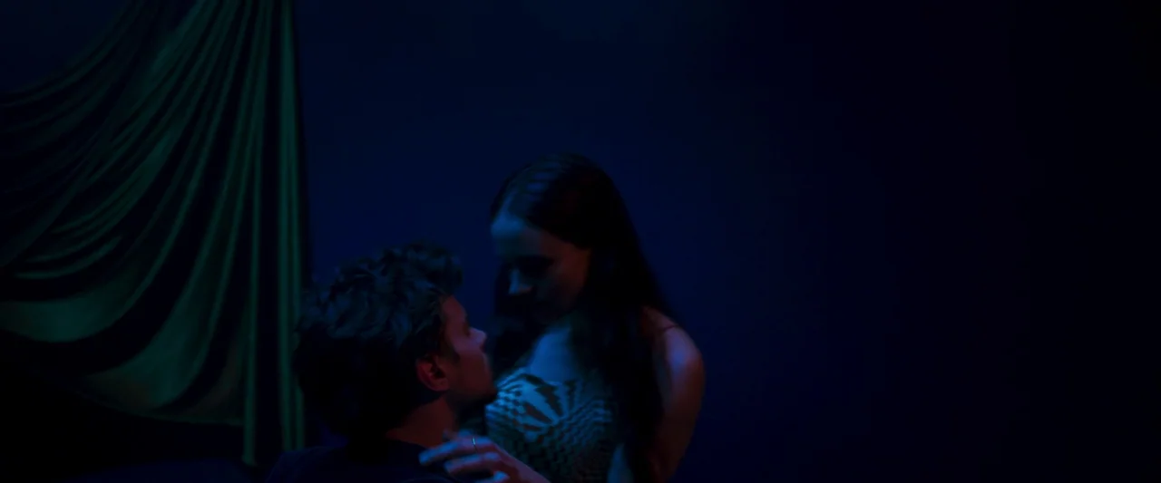 Stopmotion (2024) movie still: medium — A dark space is partially illuminated by blue and green light sources. A man and a woman stand close to each…