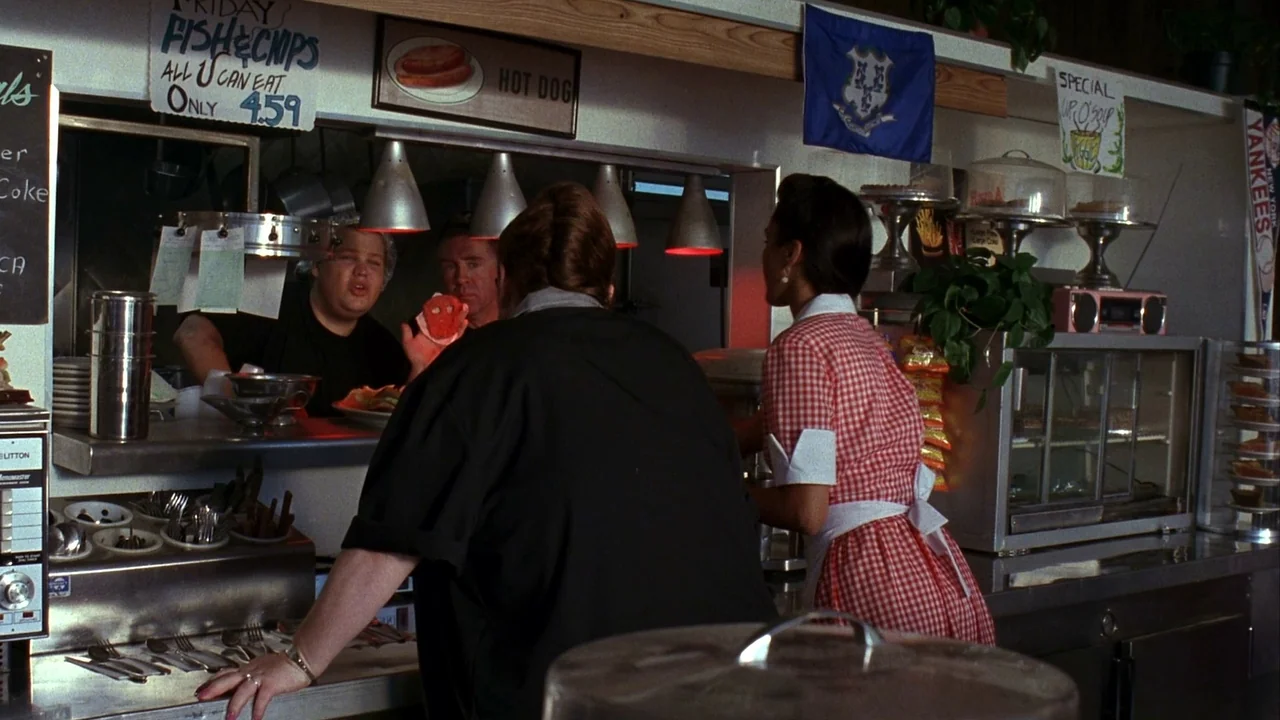 Jason Goes To Hell (1993) movie still: medium — A classic American diner interior with white walls, menus, and a service counter. A woman in a…