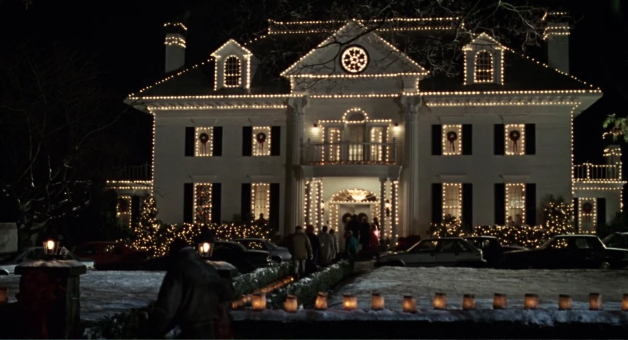 Jumanji (1995) movie still: establishing — A large two-story colonial style house is decorated with extensive strings of Christmas lights. A small…
