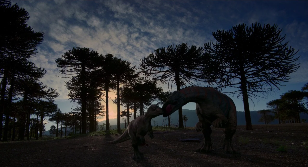 Voyage of Time (2016) movie still: wide — A dense grove of tall, thin conifer trees stands against a sunrise sky. A large dinosaur and a smaller…
