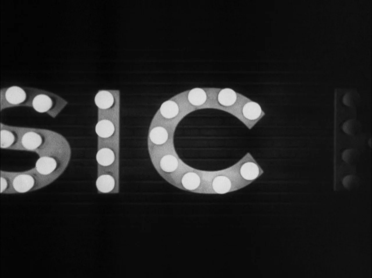 The 39 Steps (1935) movie still: closeup — A close-up view of a marquee sign featuring illuminated incandescent light bulbs. The letters spell out…