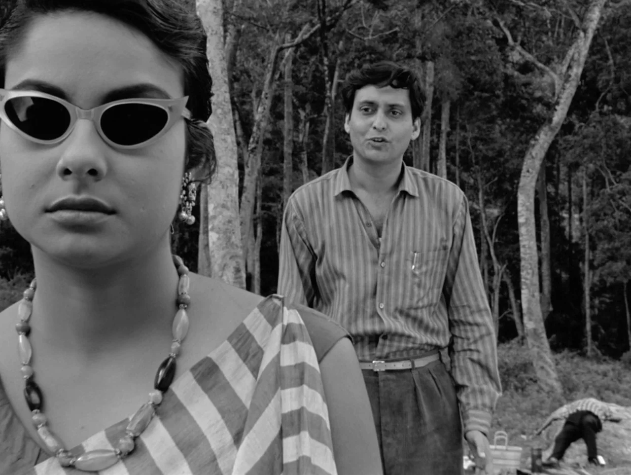 The Coward (1965) movie still: medium — A dense woodland setting features tall, slender trees and sparse underbrush in the background. A woman wears…