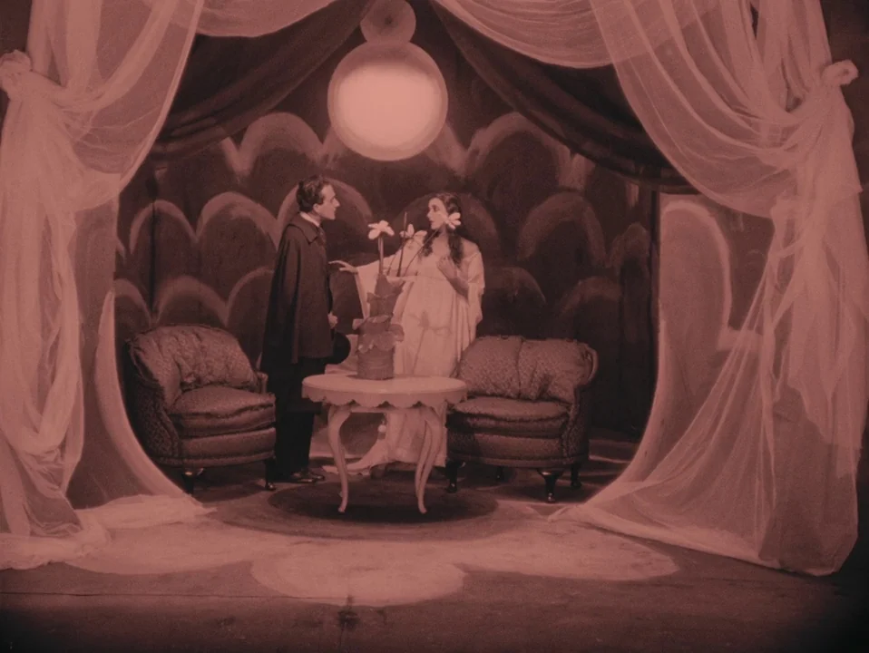 The Cabinet of Dr. Caligari (1920) movie still: fullbody — A theatrical set featuring fabric drapes and a painted backdrop with curved patterns. Two…