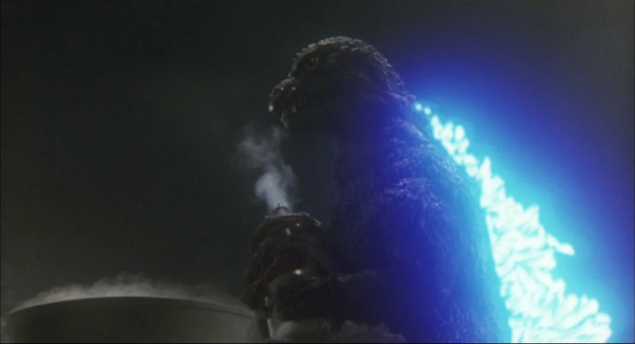 The Return of Godzilla (1984) movie still: medium — A dark night setting features a large reptilian monster viewed from the side profile. The…