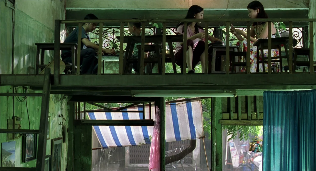 The Vertical Ray of the Sun (2000) movie still: wide — An aged interior with green walls features an elevated wooden mezzanine with four people. The…
