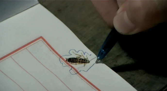 The Boys From Fengkuei (1983) movie still: closeup — A notebook with red-lined grid paper lies flat on a dark wooden surface. A hand uses a blue…