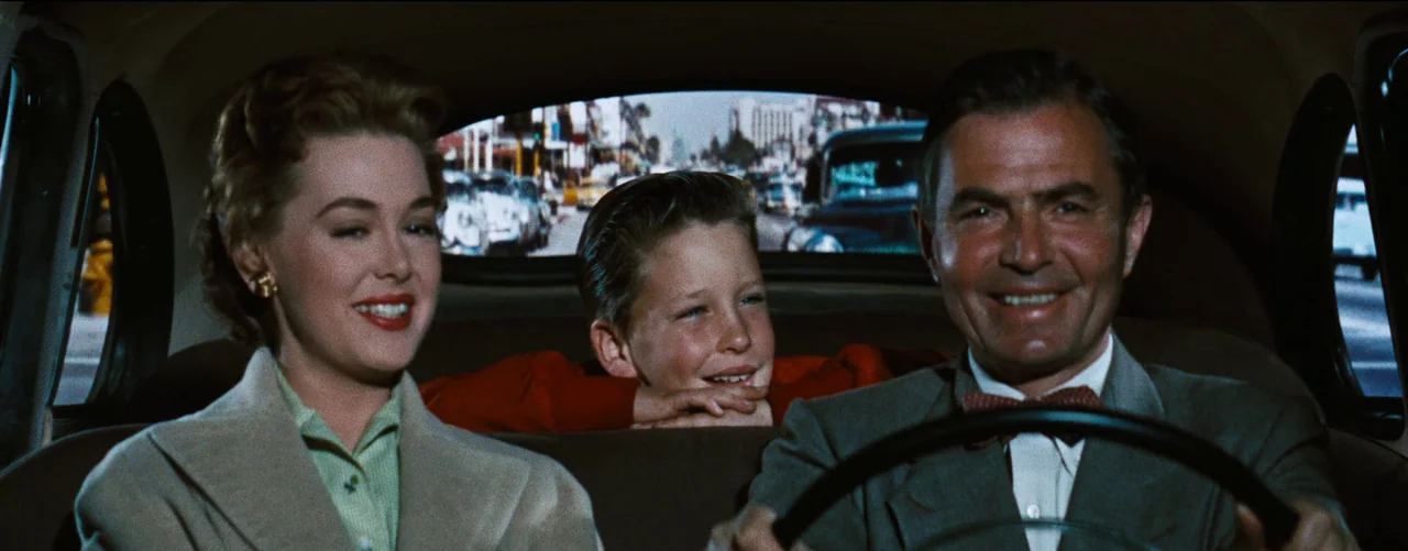 Bigger Than Life (1956) movie still: medium — Three people sit in the front and rear seats of a vintage automobile. They face forward while smiling…