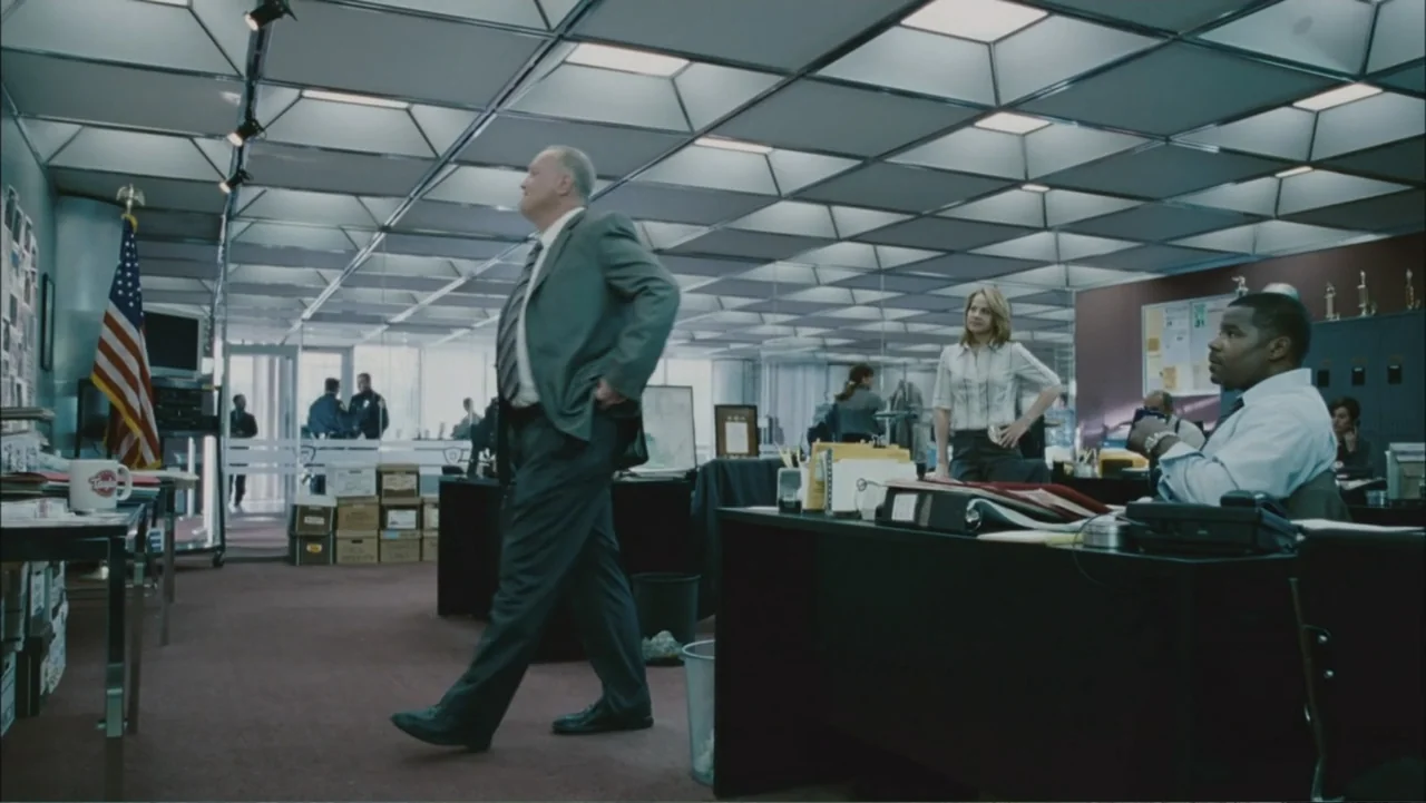 The Stepfather (2009) movie still: fullbody — A busy police department office features rows of desks under a fluorescent drop ceiling. An older man…