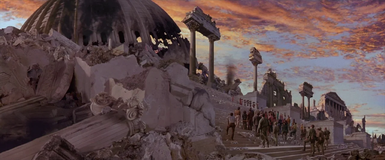 Mars Attacks! (1996) movie still: wide — A destroyed monumental structure features a collapsed dome and fallen Greco-Roman columns. People walk up…