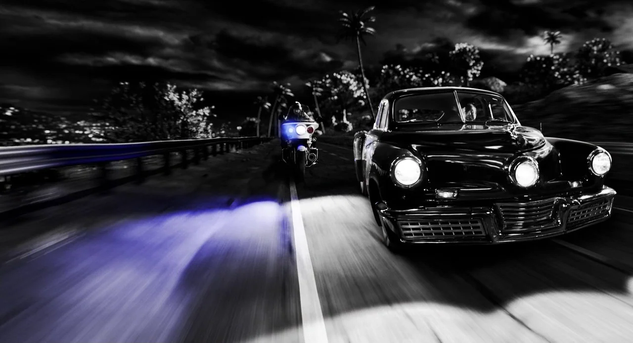 Sin City: A Dame to Kill For (2014) movie still: wide — A night road lined with palm trees under a dark cloudy sky. A police officer on a motorcycle…