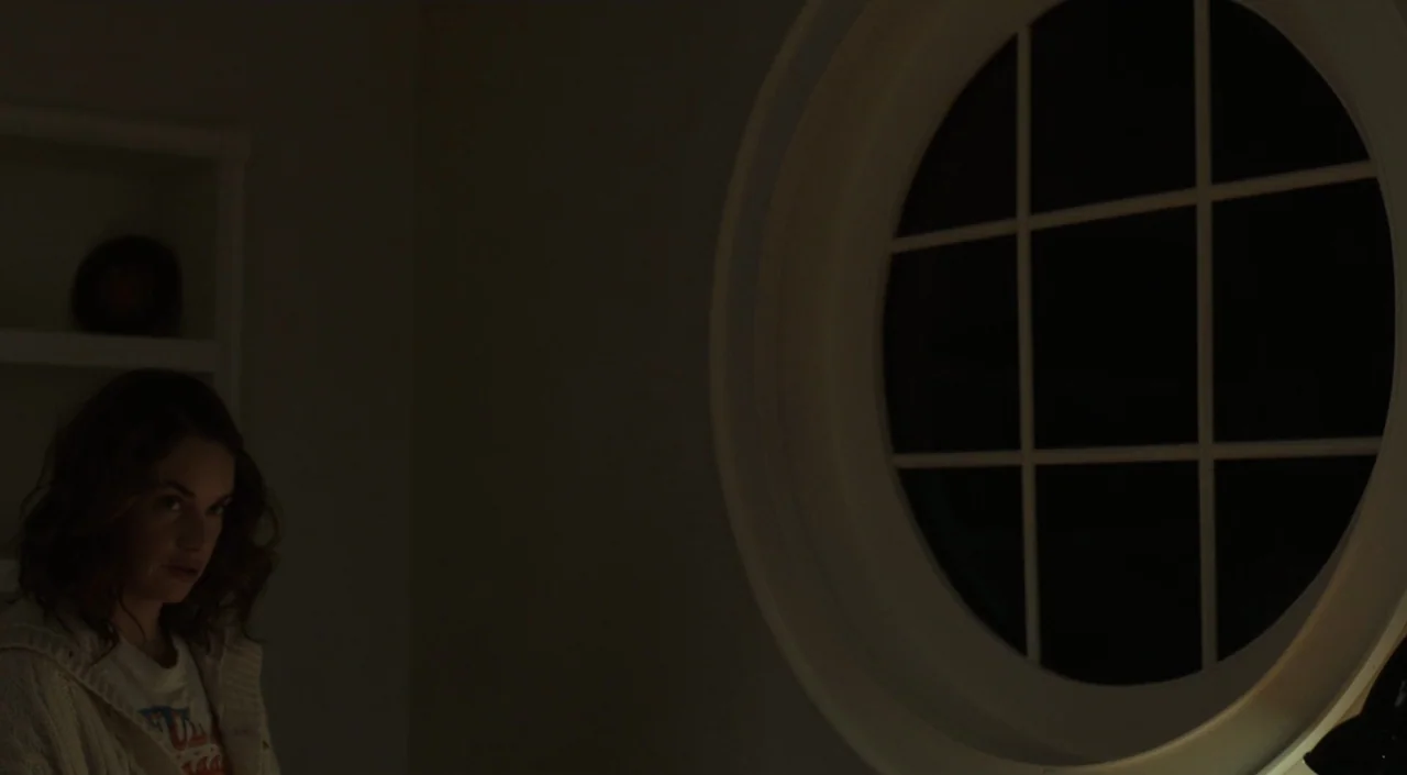 I Am The Pretty Thing That Lives In The House (2016) movie still: medium — A dimly lit room features a prominent circular window on the right wall.…