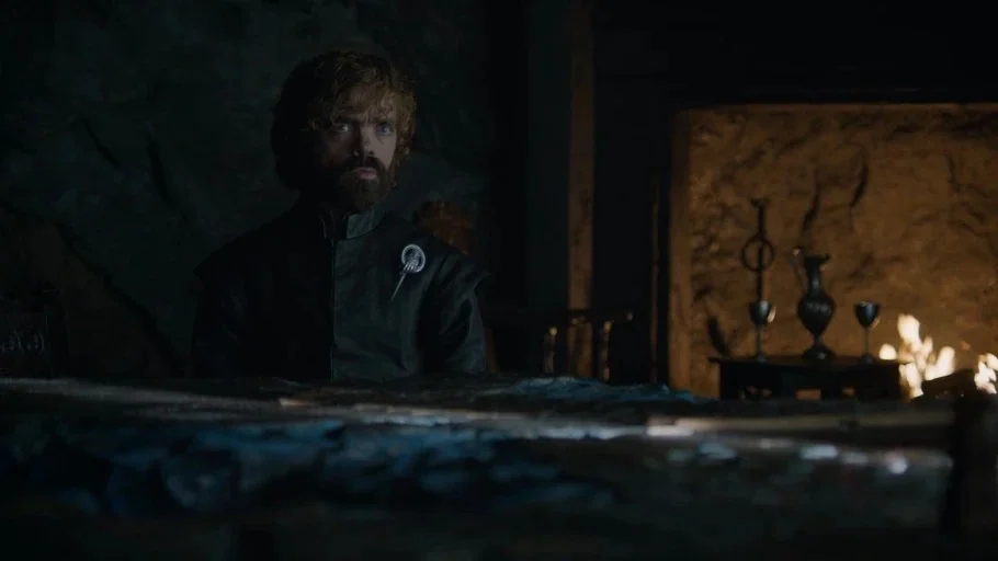 Game of Thrones (2017) movie still: medium — A dimly lit, rugged stone chamber contains a large map table and a fireplace. A man in a dark doublet…