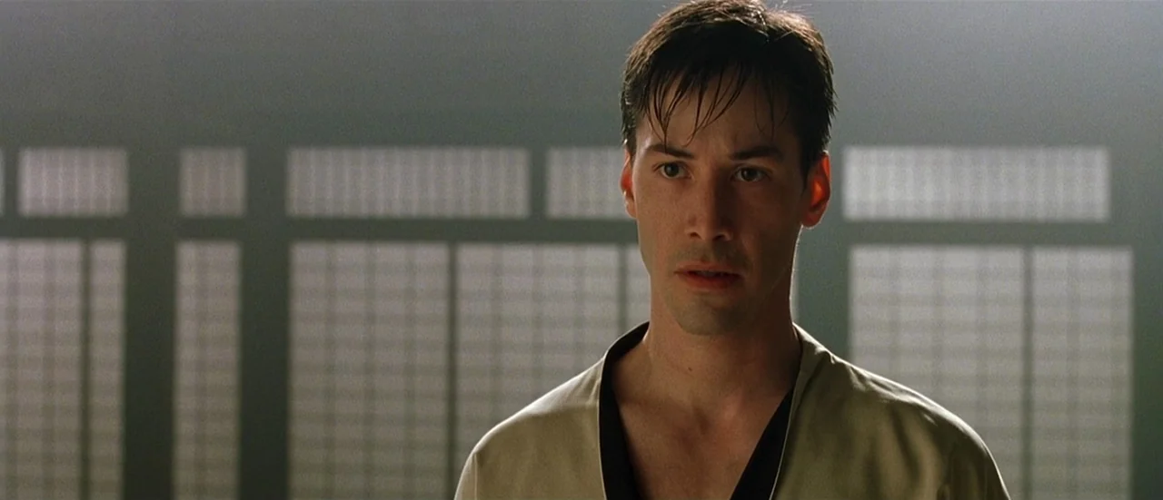 The Matrix (1999) movie still: medium — A spacious room features traditional Japanese sliding paper screens backlit by daylight. A man in a beige gi…