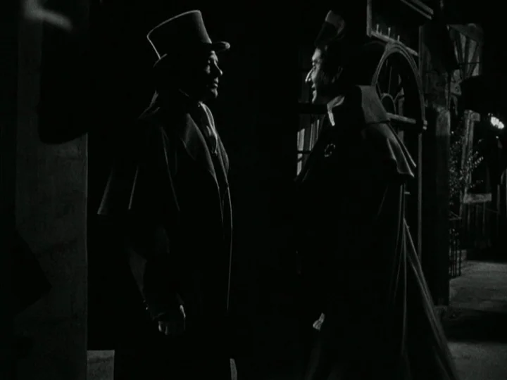 The Black Book (Reign of Terror) (1949) movie still: medium — Two men wearing period overcoats and hats stand on a darkened city street. They face…