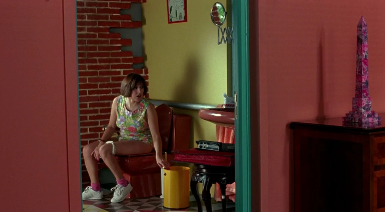 Tie Me Up! Tie Me Down! (1989) movie still: medium — A brightly colored bathroom features salmon-pink walls, a yellow trash can, and red fixtures. A…
