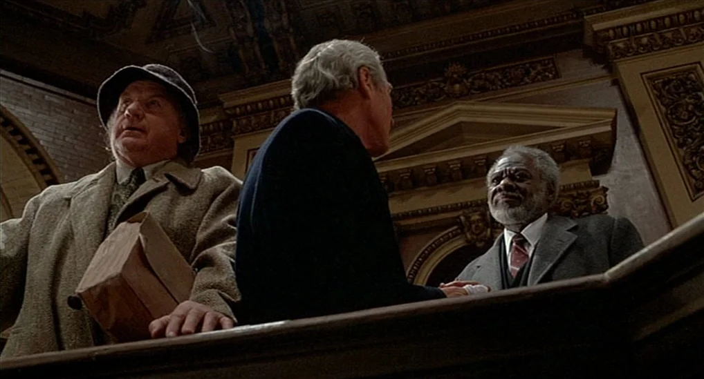 The Verdict (1982) movie still: medium — A ornate interior with carved wooden moldings and arched architecture. Three men lean against a railing…