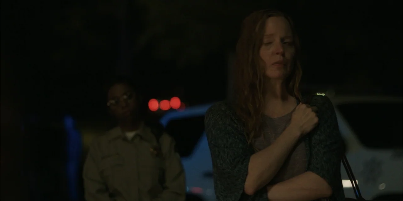 Caddo Lake (2024) movie still: medium — An outdoor parking lot at night with dark surroundings and blurred light sources. A woman stands in the…