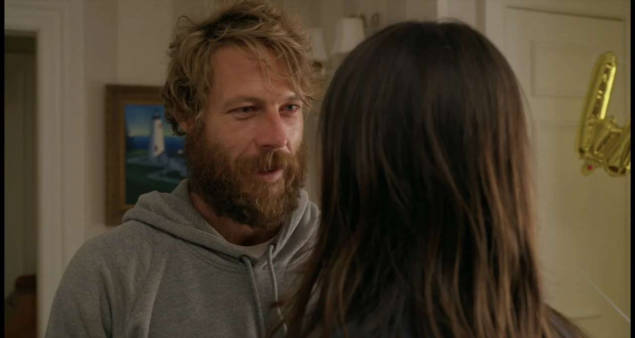 One True Loves (2023) movie still: medium — A residential room interior features a framed painting of a lighthouse on the wall. A man in a grey…
