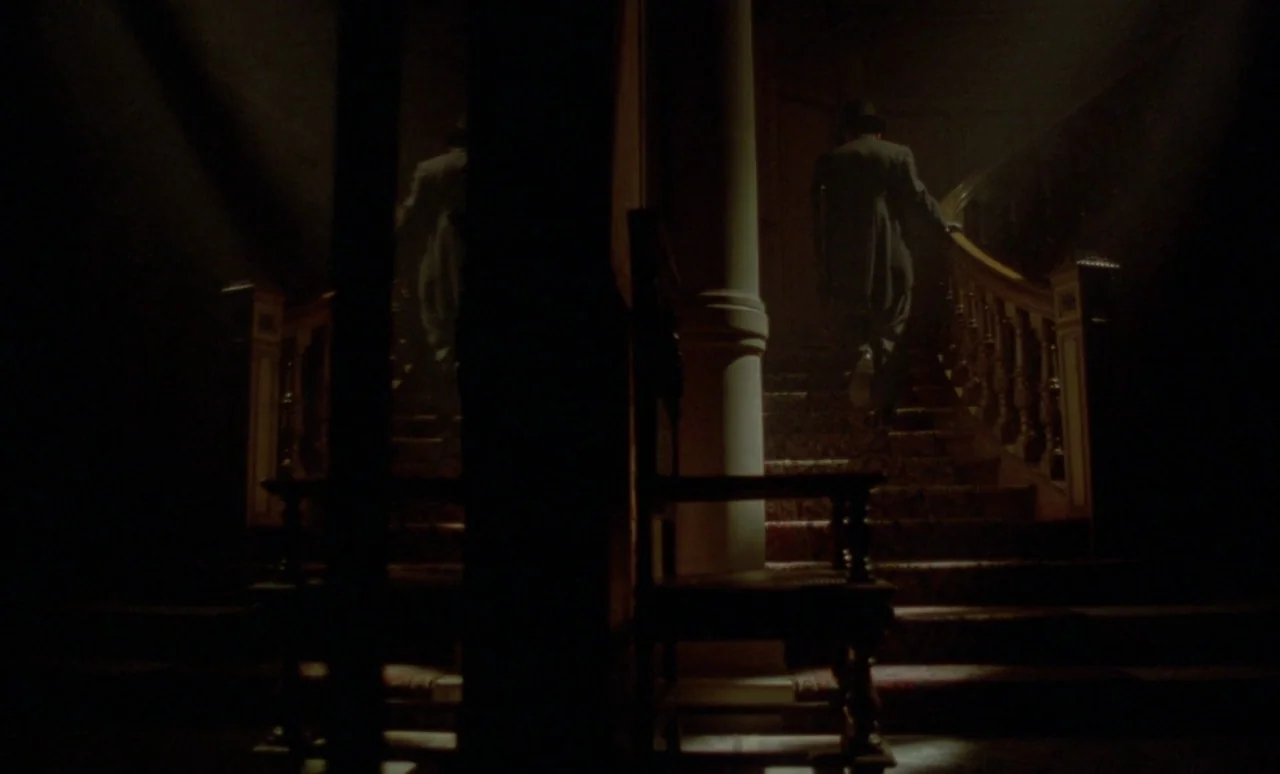 The Strange Case of Dr. Jekyll and Miss Osbourne (1981) movie still: wide — A dark, ornate interior features a wooden staircase covered in patterned…