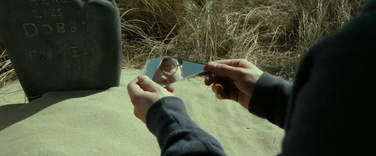Harry Potter & The Deathly Hallows Part 2 (2011) movie still: medium — A stone grave marker sits in the sandy dunes next to tall dried grass. A…