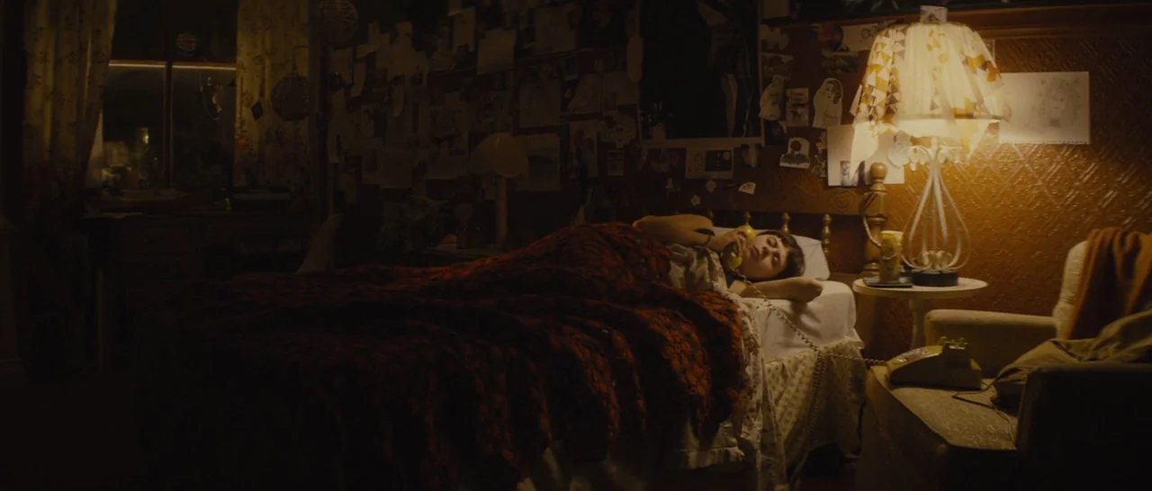 The Diary of a Teenage Girl (2015) movie still: medium — A cluttered bedroom with walls covered in paper clippings and a warm bedside lamp. A young…