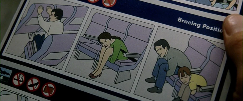 Fight Club (1999) movie still: closeup — A close-up view of an airline safety card held by a human thumb. The card features cartoon illustrations of…