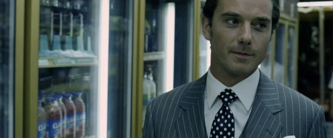 Constantine (2005) movie still: medium — A brightly lit commercial refrigeration aisle with glass doors showing bottled beverages behind. A man in a…