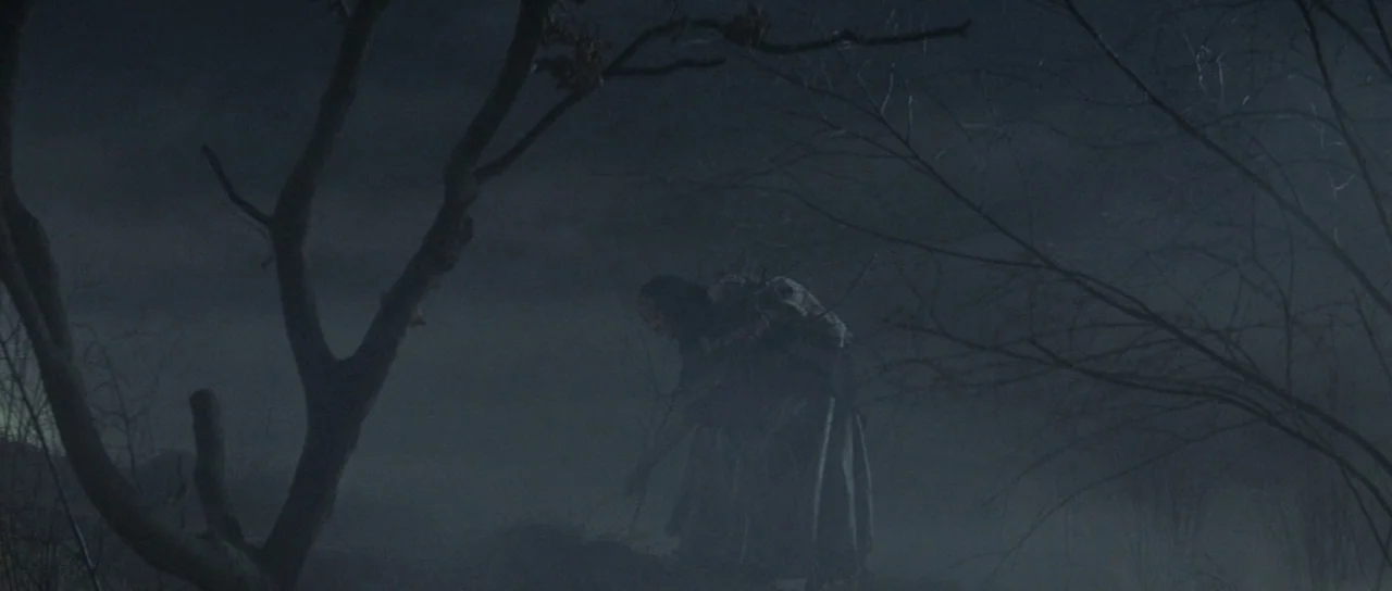 The Masque of the Red Death (1964) movie still: wide — A misty, dark field at night features bare, gnarled tree branches framing the composition. A…