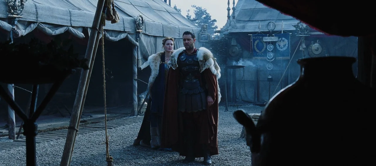 Gladiator (2000) movie still: fullbody — A military encampment features rows of heavy canvas tents on a gravel ground surface. A man in Roman armor…