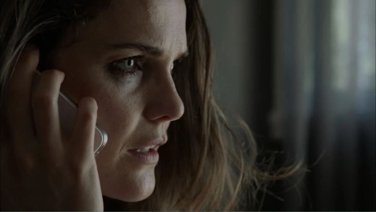 Dark Skies (2013) movie still: closeup — A dimly lit room with a window covered by a thin translucent curtain. A woman with long hair looks…