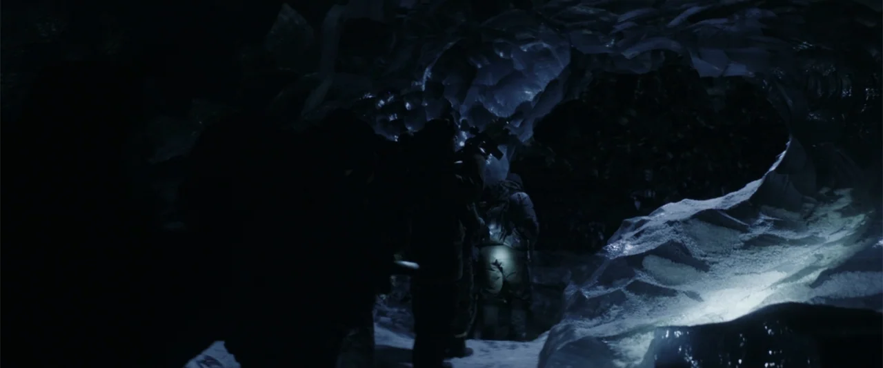 The Tomorrow War (2021) movie still: medium — An ice cave interior features jagged crystalline walls and a snowy floor in darkness. A group of…