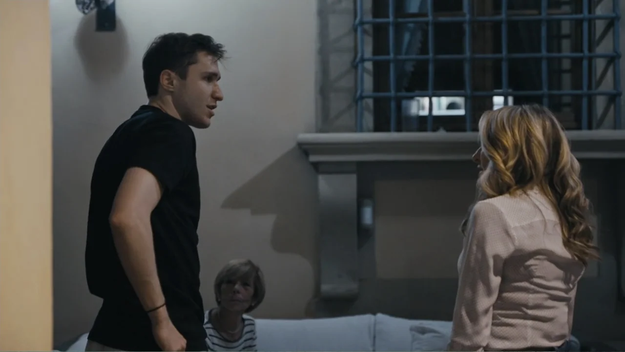 Federico Chiesa - Back on Track (2023) movie still: medium — A living room features a barred window in the background and white upholstered…