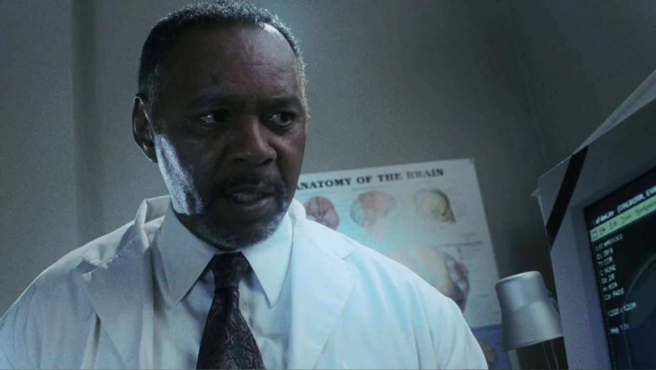 The Butterfly Effect (2004) movie still: medium — A medical office features a wall chart showing the anatomy of the brain. A middle-aged doctor in a…