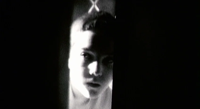 Brand Upon the Brain! (2006) movie still: closeup — A person stands in a dark space, highlighted by a vertical slit of light. The face is centered…