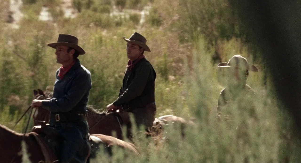 Ride In The Whirlwind (1966) movie still: medium — Three men on horseback ride through a tall grassy field in the daylight. The riders wear…