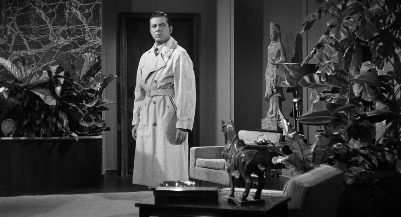 The Fearmakers (1958) movie still: fullbody — A spacious office interior features marble walls, large potted plants, and ornate statuary. A man in a…