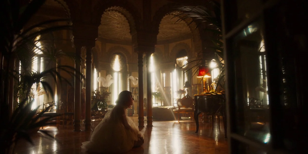 Paradise Hills (2019) movie still: wide — A spacious room features ornate Moorish-style arched pillars and large windows with bright light. A woman…