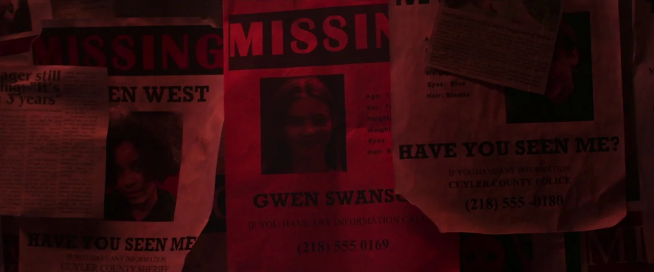 The Silencing (2020) movie still: closeup — Several paper missing persons flyers are pinned together on a dimly lit dark wall. The red lighting…