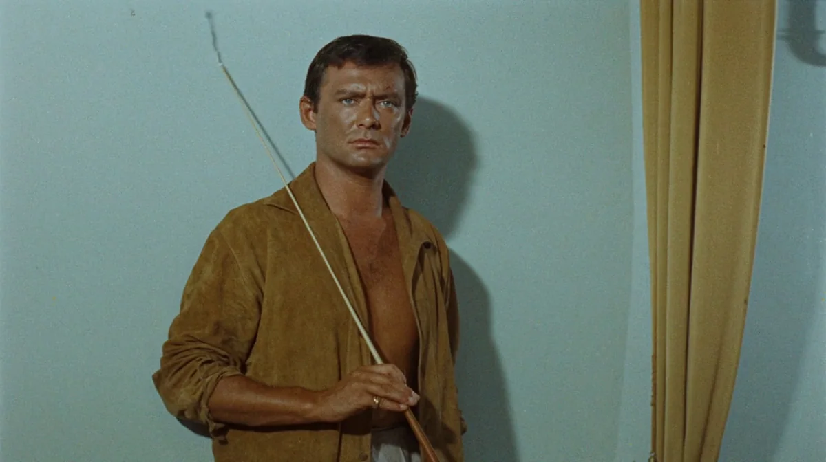 Purple Noon (Plein Soleil) (1960) movie still: medium — A room with a solid light-blue wall and a single tan curtain panel. A man poses in front of…