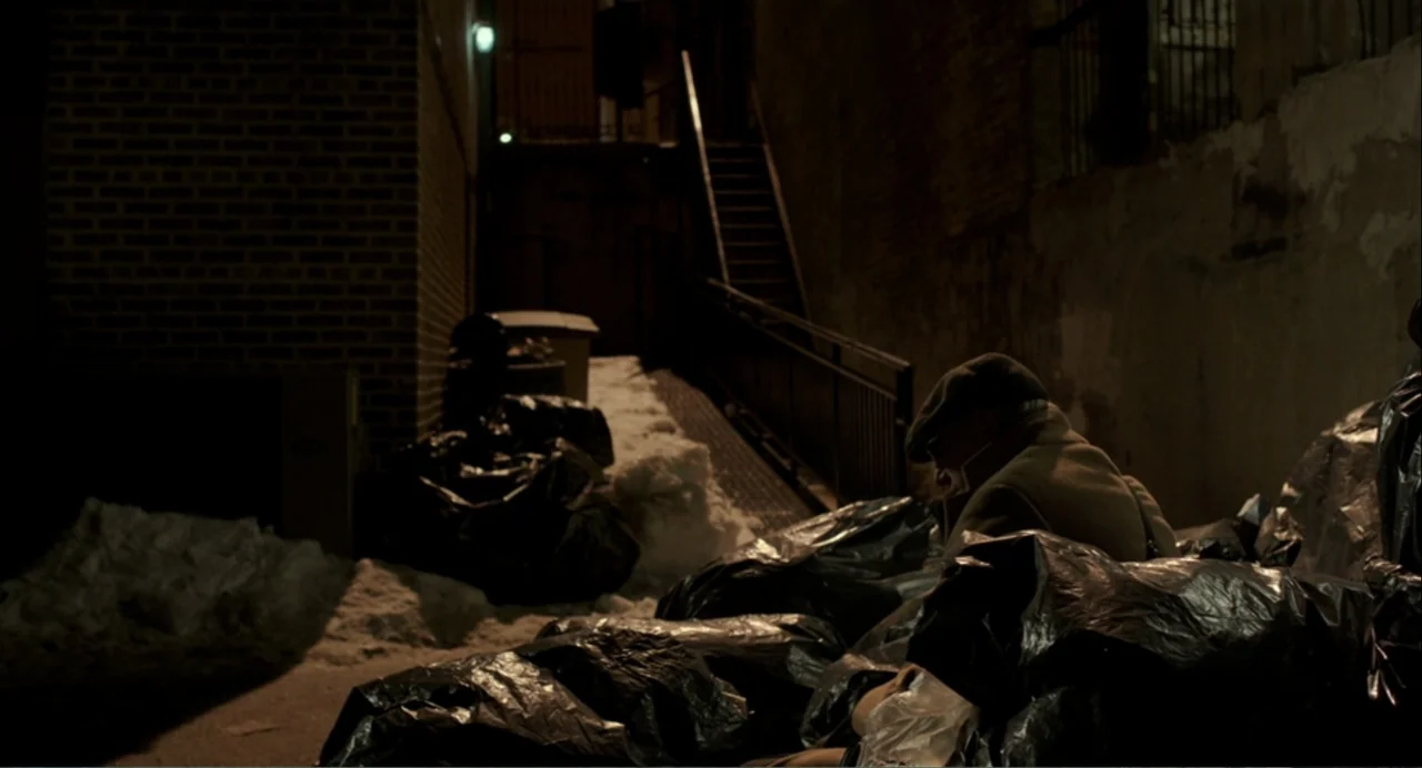 Norman: The Moderate Rise and Tragic Fall of a New York Fixer (2016) movie still: medium — An urban alleyway features a brick wall, metal staircase,…