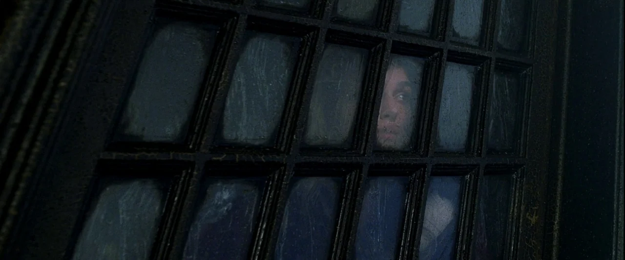 Pirates of the Caribbean: The Curse of the Black Pearl movie still: closeup — A dark, multi-paned door with visible dust or smudges on the glass. A…