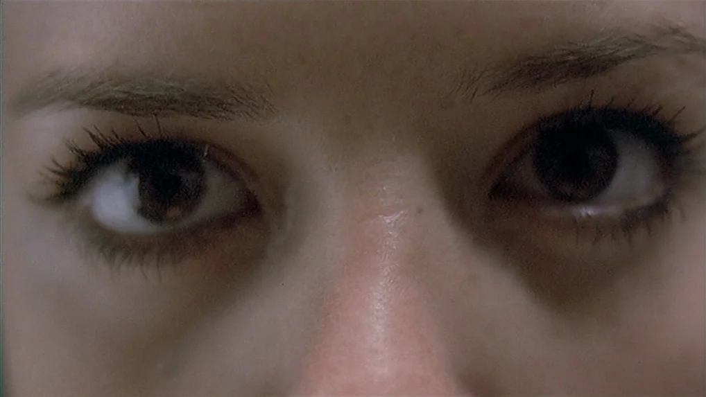 Battle In Heaven (2005) movie still: closeup — An extreme close-up focuses on the upper face of a woman. Dark brown eyes look directly toward the…