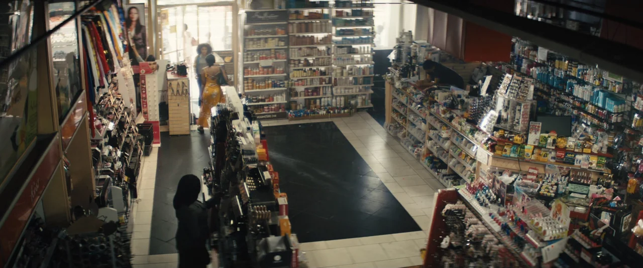 The Sun Is Also a Star (2019) movie still: wide — A cluttered interior of a beauty supply store features tall shelves stocked with hair products. A…